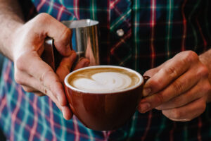Holding a cappuccino in two hands.