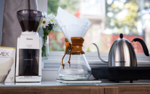 A Chemex coffee maker with filter, grinder on the left, kettle on the right.