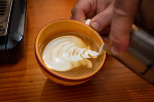 Pouring a latte with latte art, mid pour.