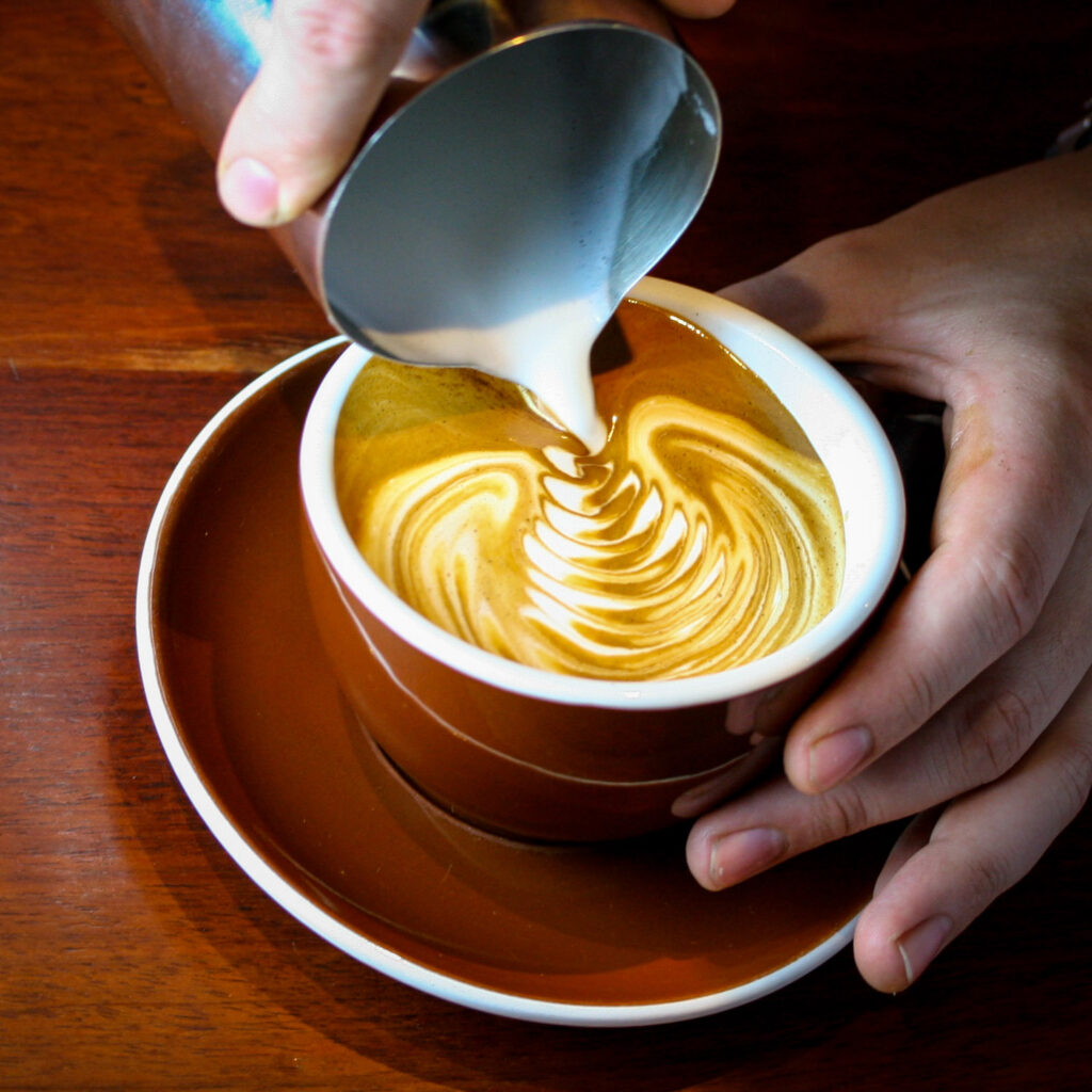 Pouring a complex rosetta pattern in a latte.