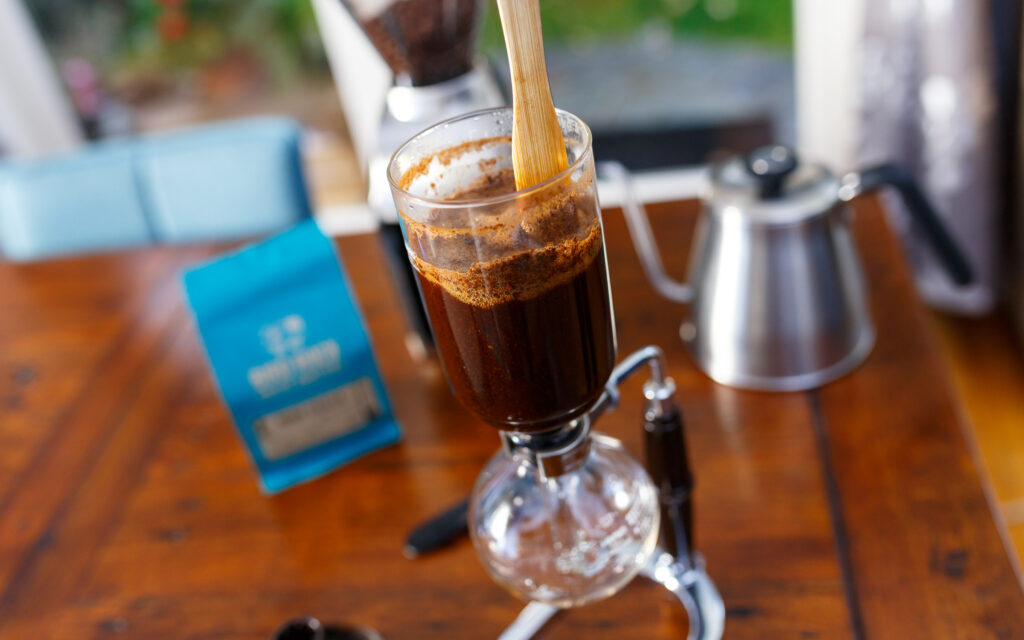 Brewing coffee with a siphon coffee maker, stirring the coffee slurry.