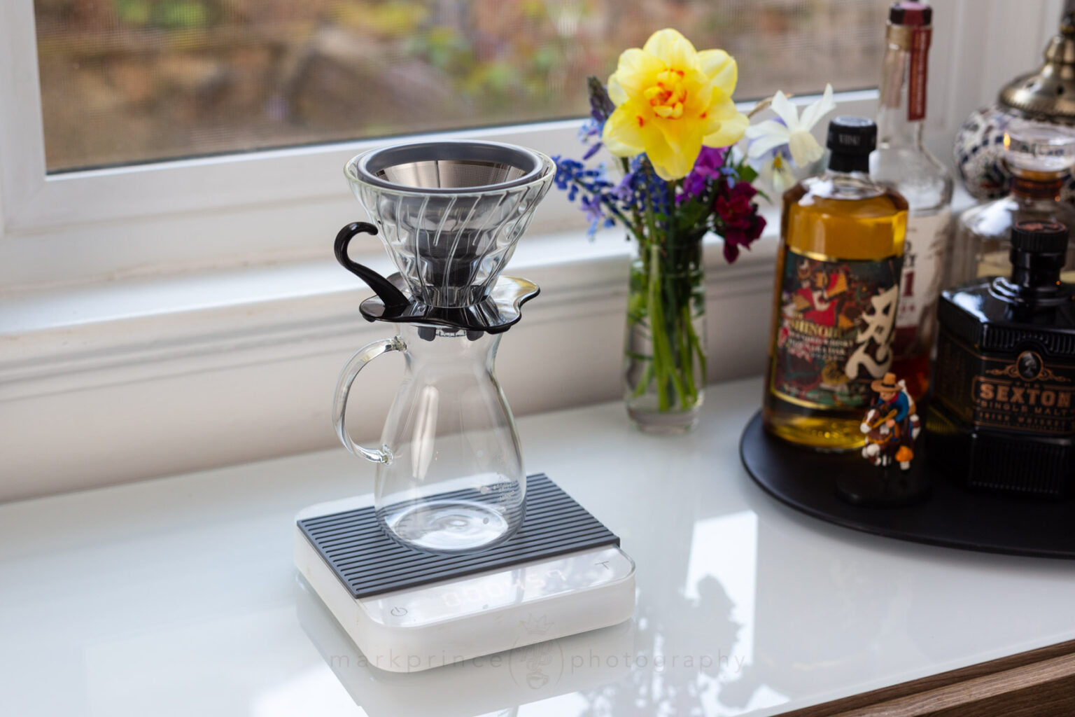 The Kone Mini sitting inside a glass Hario V60 filter holder on top of a Hario coffee beaker.